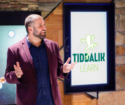 Tiddalik team member addresses clients in front of a Tiddalik frog design on a screen